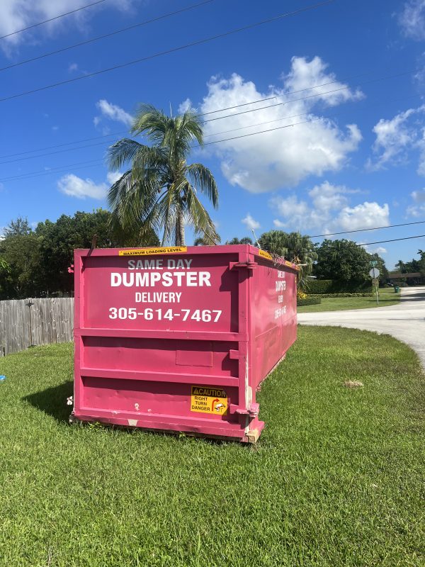 Roll off dumpster at a Miami construction site with palm trees in background